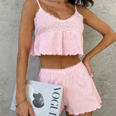Woman wearing a pink lace top and shorts holding a magazine against a gray background